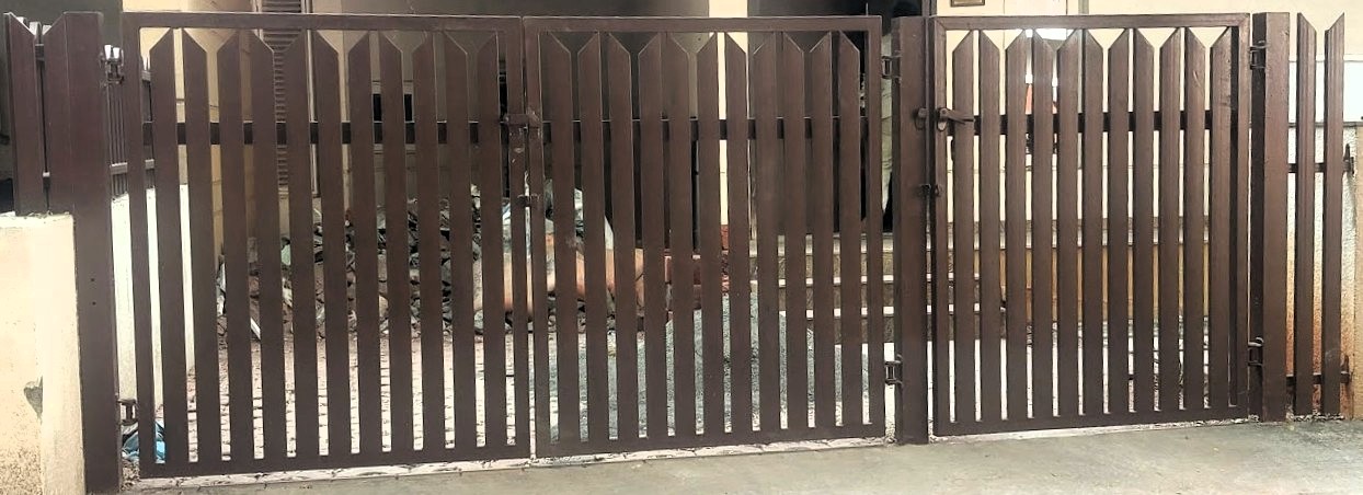 Modern entrance gate combining black metal with horizontal wooden panel accents.